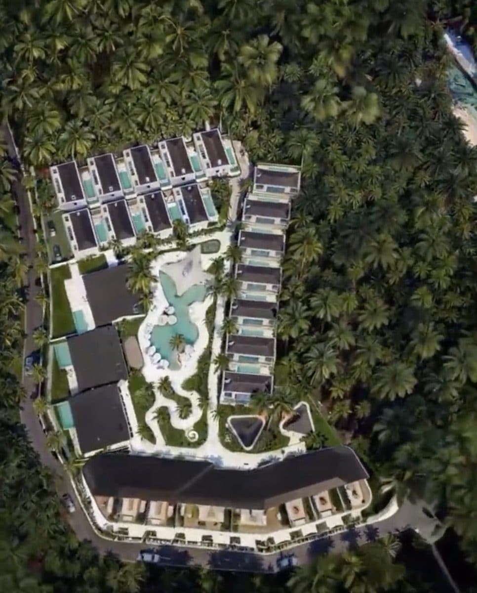 Aerial view of the first stage: villas and an apartment building around a central pool in dense tropical planting